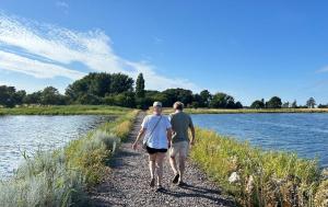 a man and woman walking down a path next to a river at TheGilgahouse Fjordroom in Nakskov