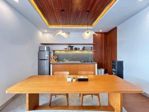 a dining room with a wooden table and a kitchen at Sudut Padi Villa Ubud by Omkara Experience in Ubud