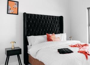 ein Bett mit einem schwarz gepolsterten Kopfteil in einem Schlafzimmer in der Unterkunft Orange Blossom Luxury Apartment in Sandton