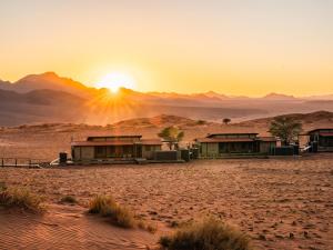 Una puesta de sol en el desierto con casas en el desierto. en Wolwedans Desert lodge, en NamibRand