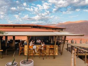 un grupo de personas sentadas en una mesa en una cubierta en Wolwedans Desert lodge, en NamibRand