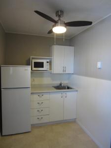 a kitchen with a white refrigerator and a microwave at Balm Beach Resort and Motel in Balm Beach