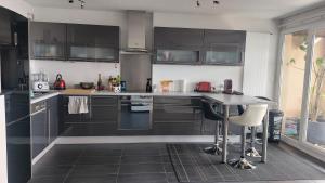 a kitchen with black cabinets and a table with chairs at Sweet home avec vue incroyable lac leman proche lausanne in Belmont-sur-Lausanne