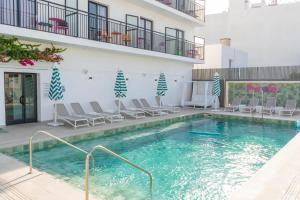 a swimming pool with chairs and a building at The Purple Hotel - Adults Only in San Antonio