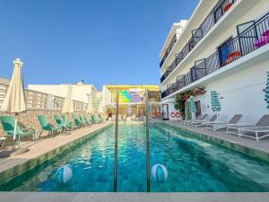 a swimming pool with chairs and umbrellas next to a building at The Purple Hotel - Adults Only in San Antonio