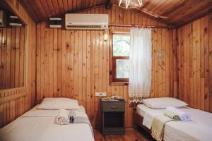 two beds in a room with wooden walls at Base Bungalows in Olympos