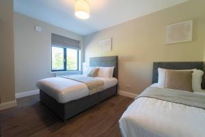 a bedroom with two beds and a window at Riverside Dingle - Luxury Apt 2 in Dingle