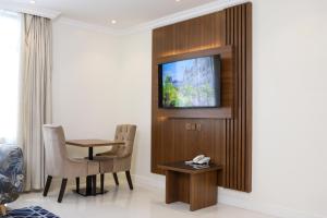 a room with a table and a television on a wall at سمت الفيحاء للشقق المخدومة - Samt Al Fayhaa Serviced Apartments in Riyadh