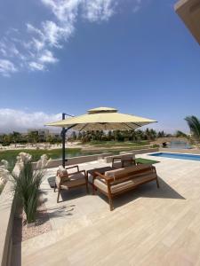 a patio with two benches and an umbrella at Villa Rotana Tulip in Salalah