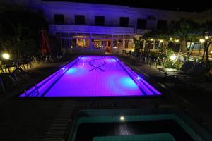 a swimming pool lit up purple at night at Garden Hotel in Pastida