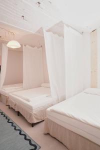 two beds in a room with white curtains at Platz für alle - geschmackvolle Gruppenunterkunft in Plagwitz