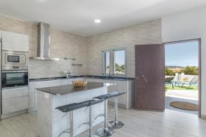 Una cocina con una gran isla con taburetes de bar. en Villa el Olivar 2, en Barbate