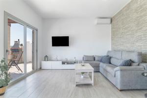 Una sala de estar con un sofá y un televisor en una pared. en Villa el Olivar 2, en Barbate