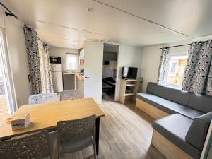a living room with a table and a couch at Bungalow Lodge 2 chambres in Lège-Cap-Ferret