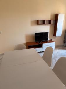 a room with a bed and a tv and chairs at Royal holiday apartamentes in Lezhë