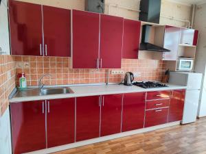 a kitchen with red cabinets and a sink at Apartment Ekaterina in Chornomorsk