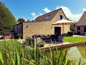 a patio with a couch and an umbrella in front of a house at B&B De Geythoek in Sijsele