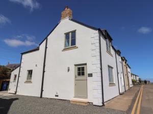 a white building with a brick chimney on a street at Puffin Cottage in Alnwick
