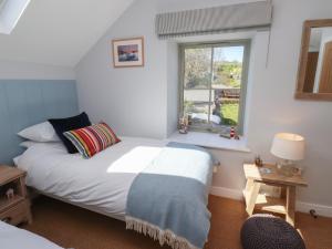 a bedroom with a bed and a window at Puffin Cottage in Alnwick