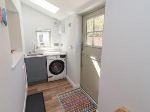 a laundry room with a washing machine and a sink at Puffin Cottage in Alnwick