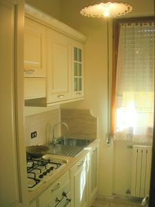 a kitchen with white cabinets and a sink and a stove at Casetta in Versilia in Viareggio