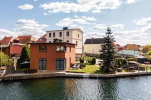 a house next to a body of water at Ferienwohnung SeaView mit Seeblick und eigener Sonnenterrasse mit Seezugang in Malchow