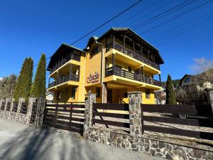 a yellow house with a fence in front of it at Casa Maria Azuga by Genco in Azuga