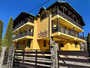 a yellow building with a fence in front of it at Casa Maria Azuga by Genco in Azuga