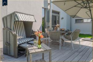 a patio with a table and chairs and an umbrella at Störtebekers Reethus mit Sauna, Kamin und E-Ladesäule in Loddin