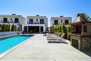 a villa with a swimming pool and lounge chairs at Glaroi 2 in Pefkohori