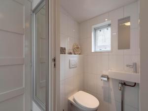 a white bathroom with a toilet and a sink at Bungalow in Sint Maartenszee near Beach in Sint Maartensvlotbrug +8 photos