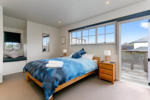 Un dormitorio con una cama y una ventana grande. en Beauty at the Lake, en Taupo