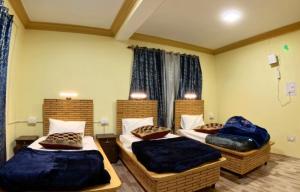 three beds in a room with blue blankets and pillows at Heavens Orchard in Manāli