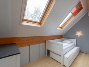 een zolderkamer met een bed en 2 ramen bij Holiday Home by Beach in Ooghduyne in Julianadorp