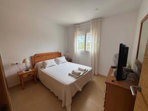 a bedroom with a bed and a television in it at Condado de Alhama Jardin 4 SV86 in Alhama de Murcia