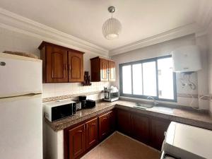 a kitchen with wooden cabinets and a white refrigerator at appartement a hassan rabat in Rabat