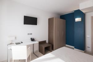 ein Zimmer mit einem Schreibtisch und einem Fernseher an der Wand in der Unterkunft Hotel Palmensis in Marina Palmense