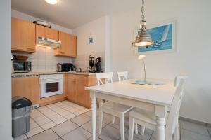 una cucina con tavolo e sedie bianchi di Leuchtturm a Stakendorfer Strand