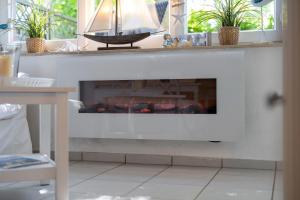 un soggiorno con un camino con una barca sopra di Leuchtturm a Stakendorfer Strand