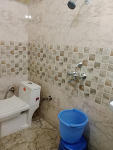 a bathroom with a toilet and a blue bucket at Landour Apartment Beauty and Charm Kothri- Summer n Snow in Mussoorie
