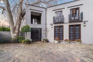 a white house with a tree and a courtyard at Ataraxia Place in Krugersdorp