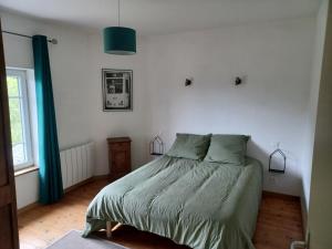 a bedroom with a bed with a green comforter at les chambres du Kergolo in Plouézec