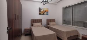 a room with two beds and a window at ConfortTek apartment in Boumhel El Bassatine