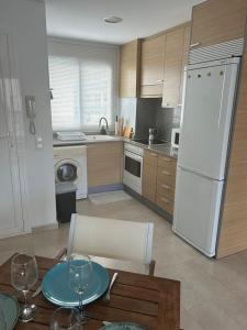 a kitchen with a table and a white refrigerator at Chula Vista Apartamento, 200m de la playa, piscina, parking in Daimuz