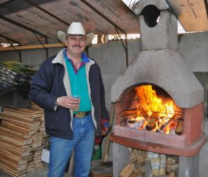 mężczyzna w kowbojskim kapeluszu stojący obok piekarnika w obiekcie Transylvania Cowboy Cottage w Klużu-Napoce