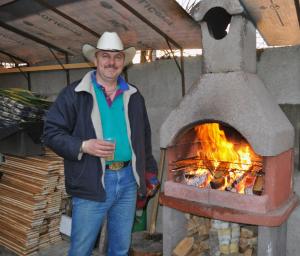 a man in a cowboy hat standing next to an oven at Transylvania Cowboy Cottage in Cluj-Napoca