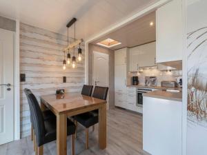 a kitchen with a wooden table and black chairs at Bungalow at Garnekuul park with garden in Callantsoog