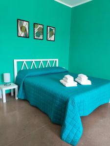 a green bedroom with a bed with a blue bedspread at Al giardino nascosto in Visco +4 photos