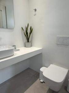 a white bathroom with a toilet and a sink at Drop off in Ermoupoli