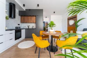 a kitchen and dining room with yellow chairs and a table at Apartamenty Panorama 5! - Z widokiem, parkingiem, nowoczesne - wKarkonosze in Jelenia Góra
